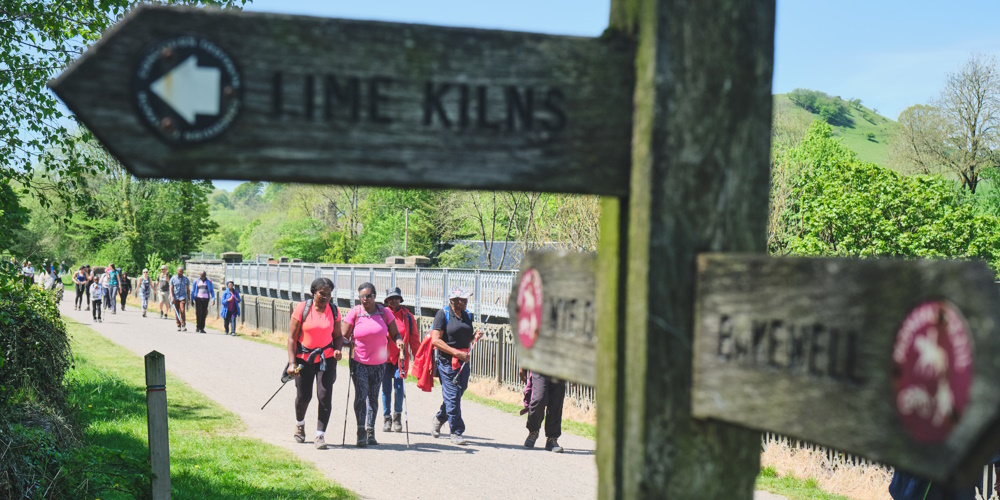 Close up of signpost on Monsal Trail with walkers in background